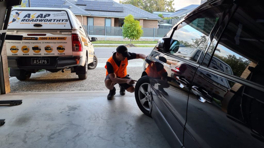 safety examiner checking the tyre tread depth of a car during a roadworthy inspection