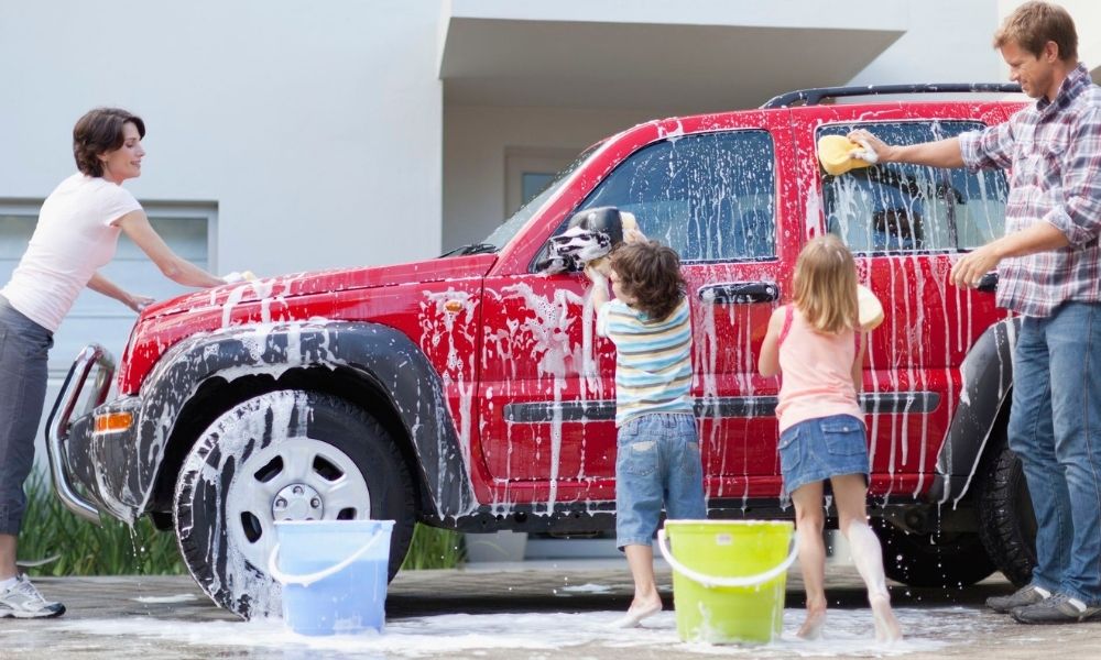 family showing kids how to wash a car
