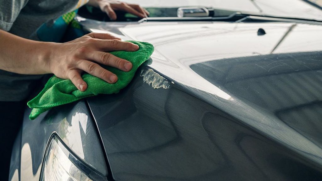 wiping down the surface of the car to fix the scratch